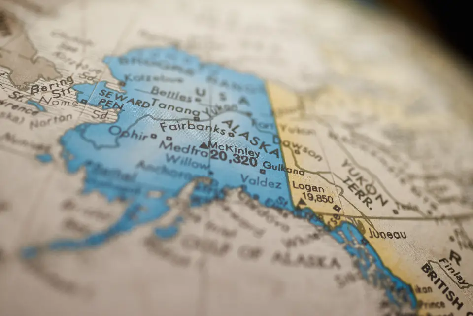 Close-up of a printed atlas showing two neighbouring regions in different colours, representing one website serving two language audiences.