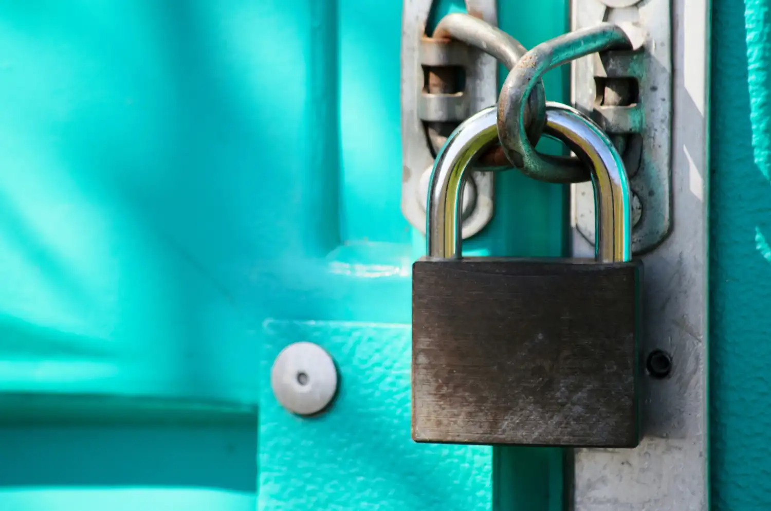 A close-up of a sturdy padlock secured on a teal door, symbolizing website security and the controlled access provided by a robots.txt file.
